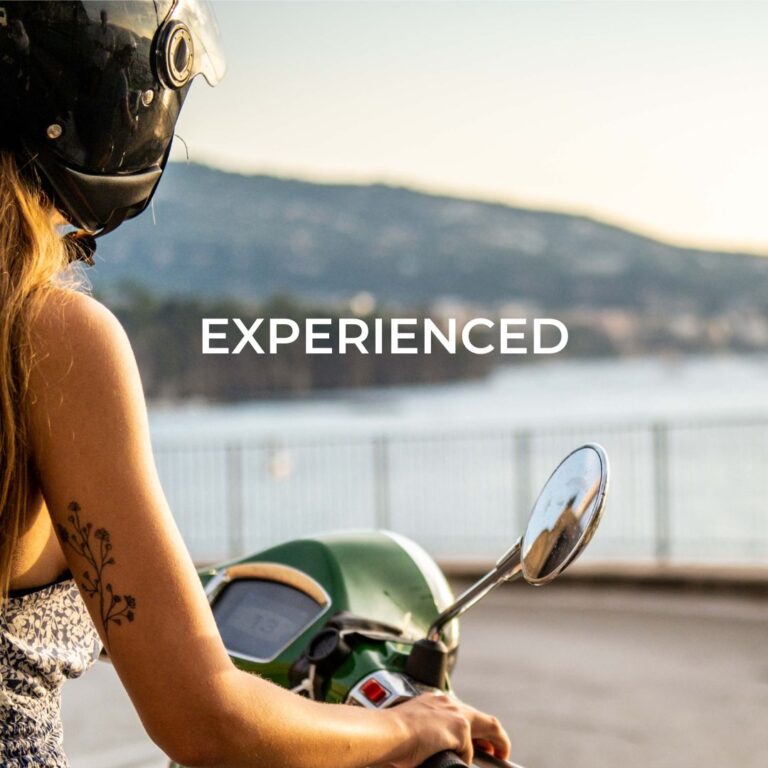 Abenteurerin auf ihrer Vespa in einer Kurve an der Amalfiküste – der perfekte Roadtrip durch Italien mit atemberaubendem Ausblick.