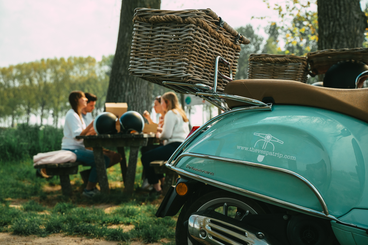 Menschen machen eine Picknickpause während der Brugge Vespa Tour.